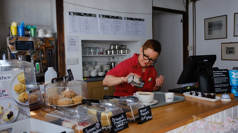 A National Trust staff member sprinkles chocolate on a freshly made cappuccino in the tear-room at at Paycocke's House